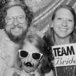 Family taking a black & white photo inside a photo booth with props