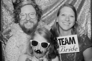 Family taking a black & white photo inside a photo booth with props